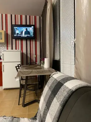 a living room with a table and a television on a wall at Квартира у моря in Pomorie