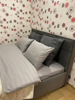 a bed with pillows on it in a room with flowers at Квартира у моря in Pomorie