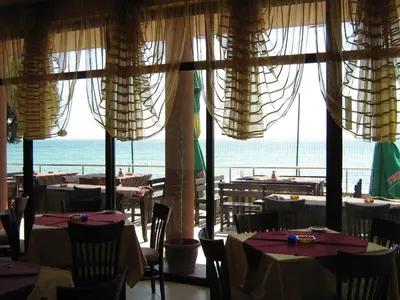 a restaurant with tables and chairs and a view of the ocean at Hotel Blian in Ravda