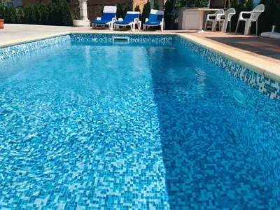 a large blue swimming pool with blue chairs in it at Apartment RAYA in Obzor