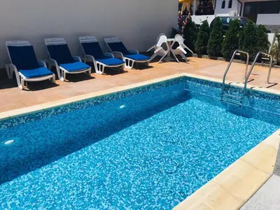 a swimming pool with blue chairs next to it at Apartment RAYA in Obzor