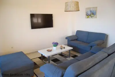 a living room with two blue couches and a tv at Coral Luxury Villas in Lozenets