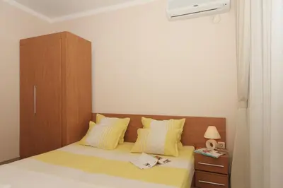 a small bedroom with a bed with a wooden headboard at Bay Apartments Sozopol in Sozopol