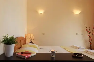 a bedroom with a bed and a table with a candle at Bay Apartments Sozopol in Sozopol