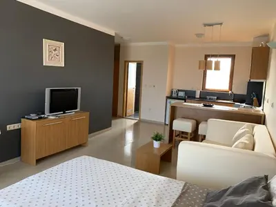 a living room with a couch and a television at Bay Apartments Sozopol in Sozopol