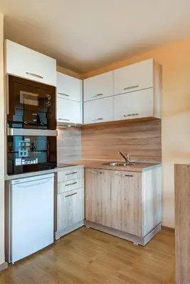 a kitchen with white cabinets and a sink at ДриймБг Апартаменти - Панорама Бийч, Несебър in Nesebar