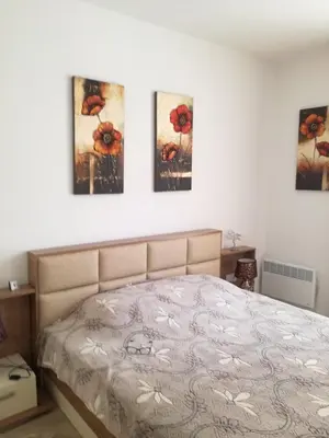 a bedroom with a bed with four paintings on the wall at Apartament Nora01 in Burgas City