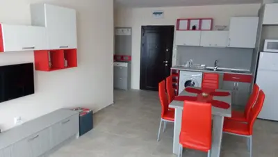a kitchen with red chairs and a table in a kitchen at Апартаменти Кастро/Castro Apartments in Tsarevo