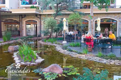 a group of people sitting at tables near a pond at Cascadas Family Resort in Sunny Beach
