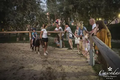 a group of people standing around a fence with a horse at Cascadas Family Resort in Sunny Beach