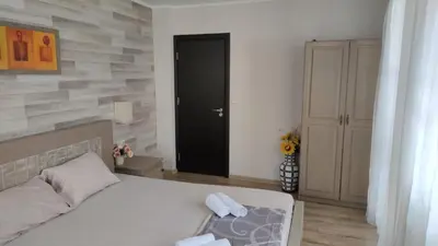 a bedroom with a white bed and a black door at Guest House Juja in Nesebar