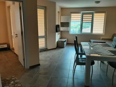 a dining room with a table and a living room at Апартаменти и стаи Мони Холидейс in Tsarevo