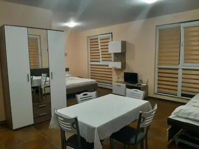 a room with a table and a room with two beds at Апартаменти и стаи Мони Холидейс in Tsarevo