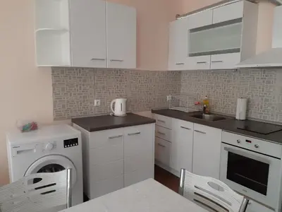 a kitchen with white cabinets and a washer and dryer at Апартаменти и стаи Мони Холидейс in Tsarevo