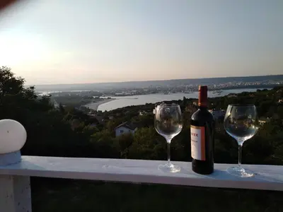 a bottle of wine and two wine glasses on a ledge at Apartament Zaliva in Varna City