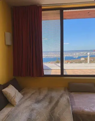 a bedroom with a bed and a large window at Apartament Zaliva in Varna City