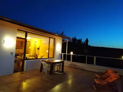 a patio with a table on a balcony at night at Apartament Zaliva in Varna City