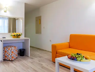 a living room with a couch and a bowl of fruit on a table at Hotel Garden Nevis - All Inclusive in Sunny Beach