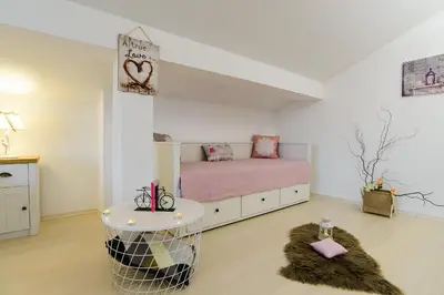 a white bedroom with a pink bed and a table at Villa Varna View in Varna City