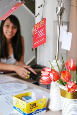 a woman standing behind a counter with a vase of flowers at Family Hotel Apolonia in Sozopol