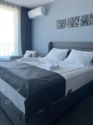 a large bed in a bedroom with a blue wall at Family Hotel Sunrise in Lozenets