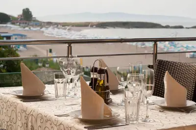 a table with glasses and napkins on a table with a view at Family Hotel Sunrise in Lozenets