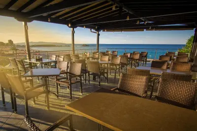 a patio with tables and chairs and the ocean at Family Hotel Sunrise in Lozenets