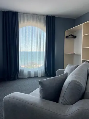 a living room with a couch and a large window at Family Hotel Sunrise in Lozenets