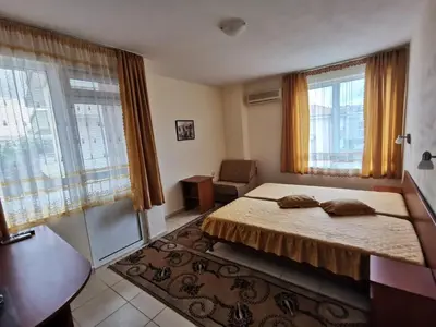 a bedroom with a bed and a chair and windows at Guest House Georgieva Ravda in Ravda