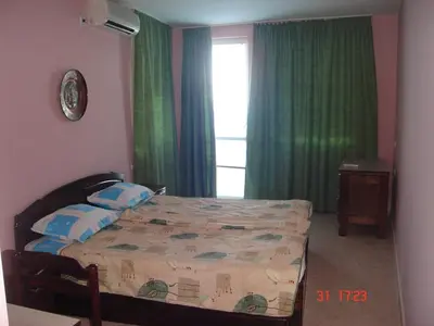 a bedroom with a bed and a window with green curtains at Guest House Rusalka in Sozopol