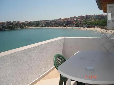 a table and chair on a balcony with a view of a beach at Guest House Rusalka in Sozopol