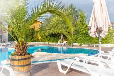 a swimming pool with white chairs and an umbrella at Sozopoli Style Club in Sozopol