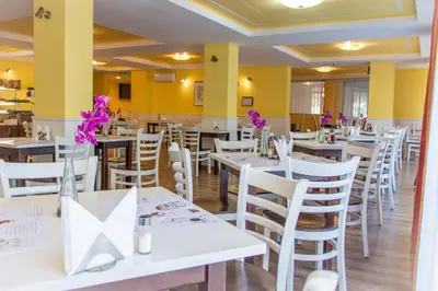 a restaurant with white tables and chairs and purple flowers at Sozopoli Style Club in Sozopol