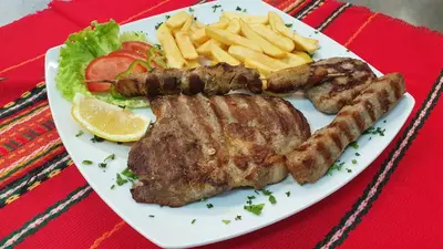 a plate of food with meat and french fries at Hotel Villa Bora in Sunny Beach