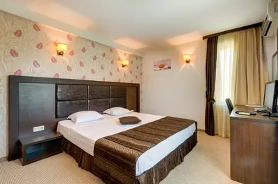 a hotel room with a large bed and a television at Siena House in Sozopol
