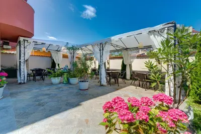a patio with tables and chairs and pink flowers at Siena House in Sozopol
