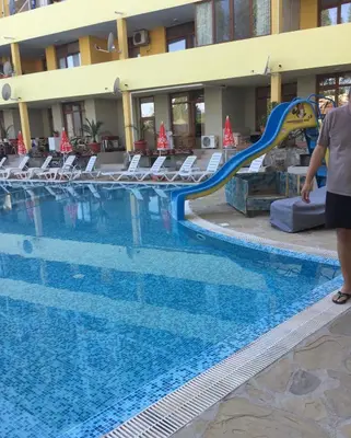 a person standing next to a slide in a swimming pool at Blue Summer in Sunny Beach