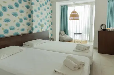 two beds in a hotel room with towels on them at Ema Hotel in Sozopol