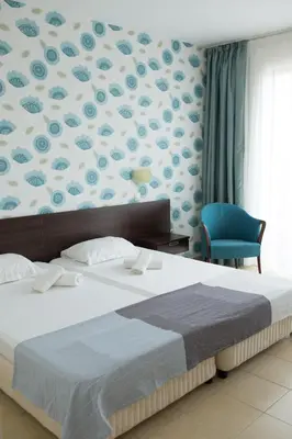a bedroom with a large bed and a blue chair at Ema Hotel in Sozopol