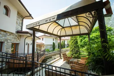a patio with chairs and a table and an umbrella at Helena VIP Villas and Suites - Half Board in Sunny Beach