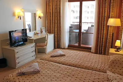 a bedroom with a bed and a desk and a television at Helena VIP Villas and Suites - Half Board in Sunny Beach