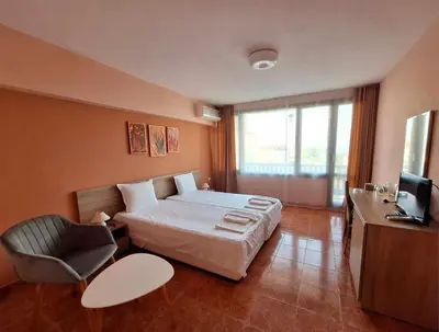 a bedroom with a bed and a chair and a television at Guest House Starata Kushta in Lozenets