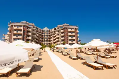 a row of chairs and umbrellas on a beach at Golden Rainbow Beach Hotel in Sunny Beach