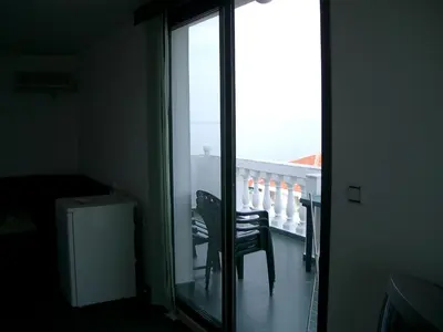 a room with a balcony with a chair and a window at Hotel Levteri in Primorsko