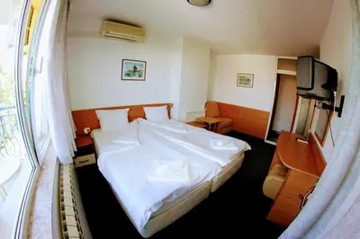 a bedroom with a white bed and a television at R&G Hotel in Nesebar