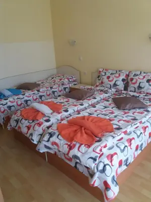 two beds in a bedroom with red and white sheets at Hotel Sirena in Primorsko