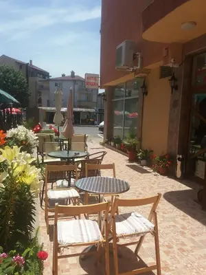 an outdoor patio with tables and chairs and buildings at Hotel Sirena in Primorsko