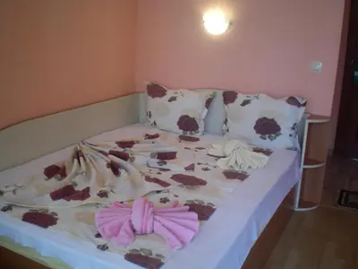 a bed with a floral comforter and pillows on it at Hotel Sirena in Primorsko