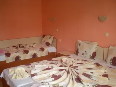 two beds in a room with orange walls at Hotel Sirena in Primorsko