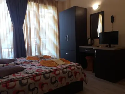 a bedroom with a bed with a desk and a television at Hotel Sirena in Primorsko